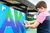 Summer Sparks Workshop, Sunderland A child wearing a mask spray paints a large canvas that is stood upright in front of him.