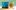 Gruesome-Glass-Painting-Autumn-2024-aspect-ratio-16-9 Two square glass frames, one painted with a haunted house design, the other with an orange and black pumpkin with a crooked smile
