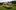 Vintage-Bus-Tour-scaled-aspect-ratio-16-9 A yellow, green and white vintage bus, parked on a piece of grass.