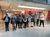 Autonomy: Connected Communities at National Glass Centre A group of young people pose for a photograph in front of a glass-walled exhibition space with white and red striped walls.