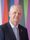 Sir David Bell KCB DL | Vice Chancellor and Chief Executive, University of Sunderland Person wearing a dark pinstripe suit, light blue patterned tie, and white shirt, standing in front of a colorful background with vertical shapes in red, blue, green, purple, and pink.