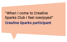 An orange speech bubble contains a quote. Black text reads: 'When I come to Creative Sparks Club I feel overjoyed' Blue text underneath reads: 'Creative Sparks participant'