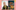 A smiling middle aged lady with cropped white hair wears a yellow lightly pattered scarf and a black top..