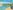 An slightly abstract city riverside city scene with a bridge over a sky blue coloured river
